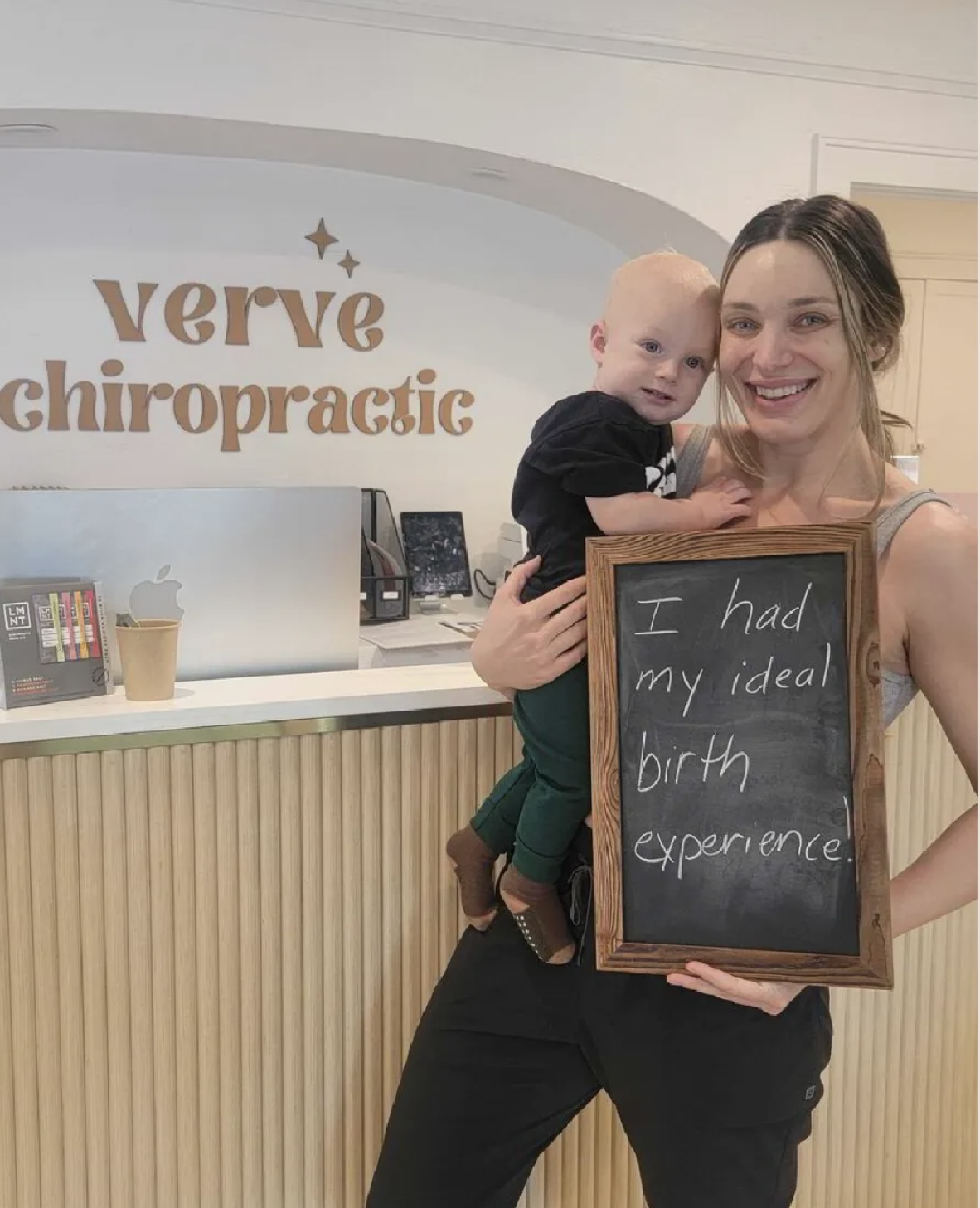 Mama holding her baby at Verve Chiropractic with chalkboard: I had my ideal birth experience