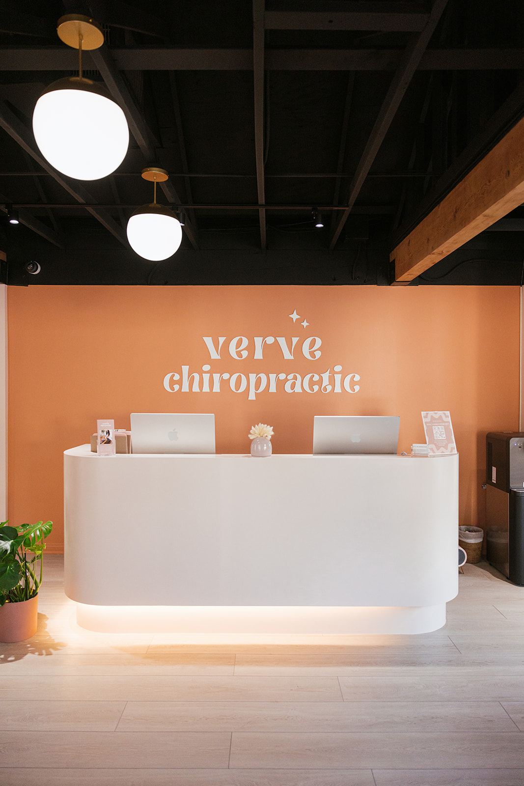 Verve Chiropractic front desk with the brand logo on the terracotta wall